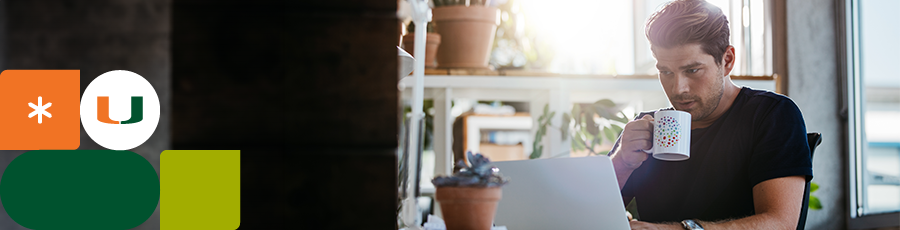 Looking at the computer screen while holding a coffee cup about how to Navigate Miami's Booming Tech Sector With ISACA Certifications