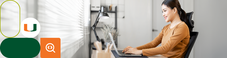 "Person working at a desk with a laptop, lamp, plant, and stationery, with natural light coming through blinds."